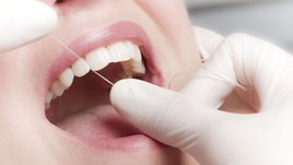 Dentalhygienikern behandelt mit Zahnseide 